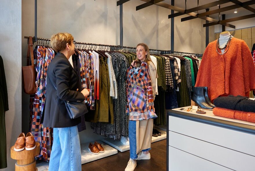 Two women are looking at clothes in a clothing store