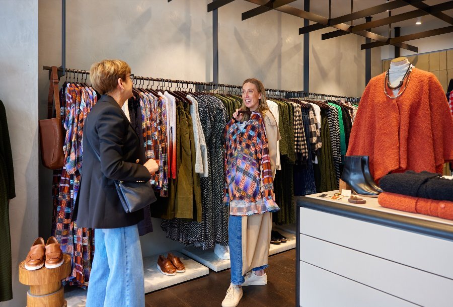 Two women are looking at clothes in a clothing store