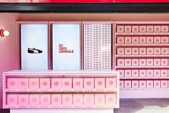 The prize giveaway counter at QV which is a booth and a counter filled with shelves of pink shoebox size gift boxes.