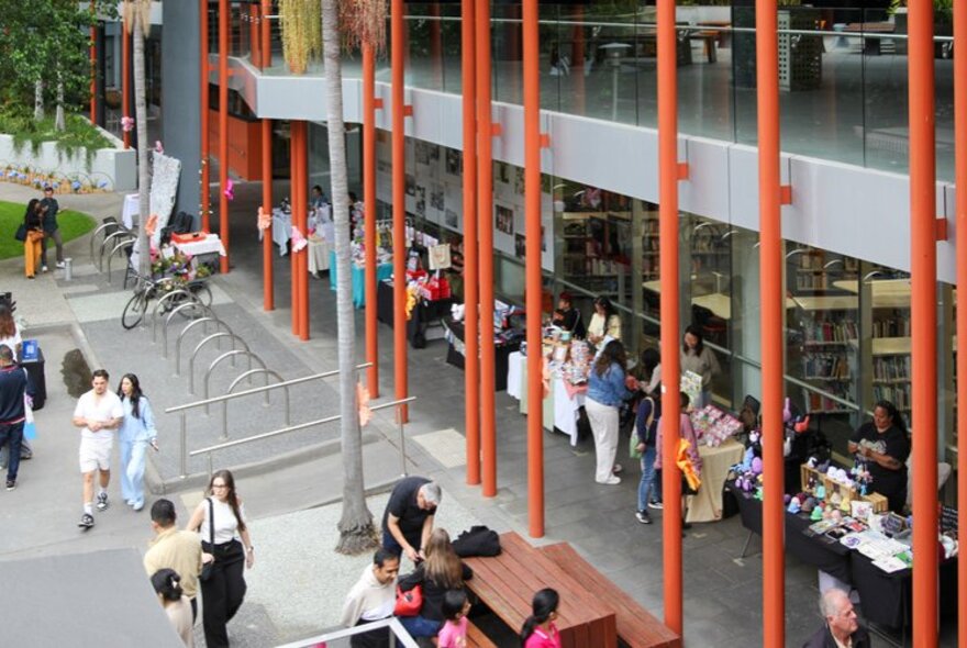 People looking at stalls under a portico at an outdoor venue.