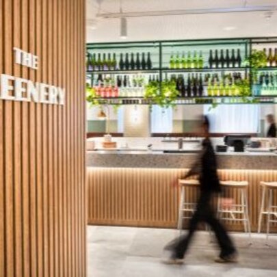 A view of the bar from the wood-lined front entrance of a cafe/restaurant, the blurred shadow of a person walking through.