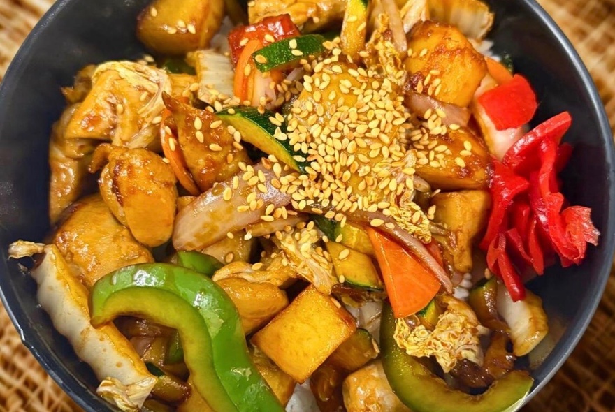 Lookong down on a bowl of Japanese food garnished with sesame seeds.
