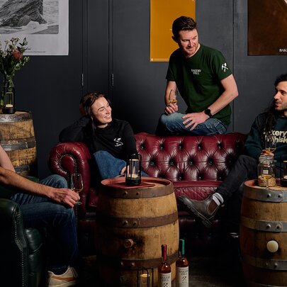 People gathered on a couch and armchairs at a distillery taking part in an introductory tasting tour.