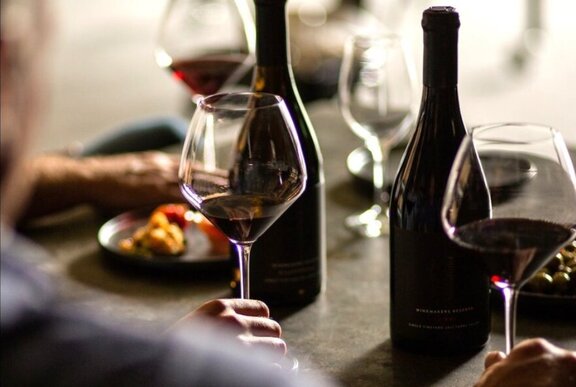 Two glasses of red wine and two bottle of wine, on a dining table in a restaurant.