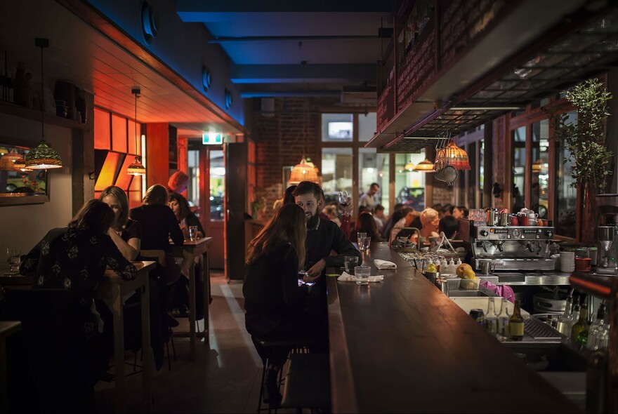 Couples enjoying drinks in a in dimly-lit bar.