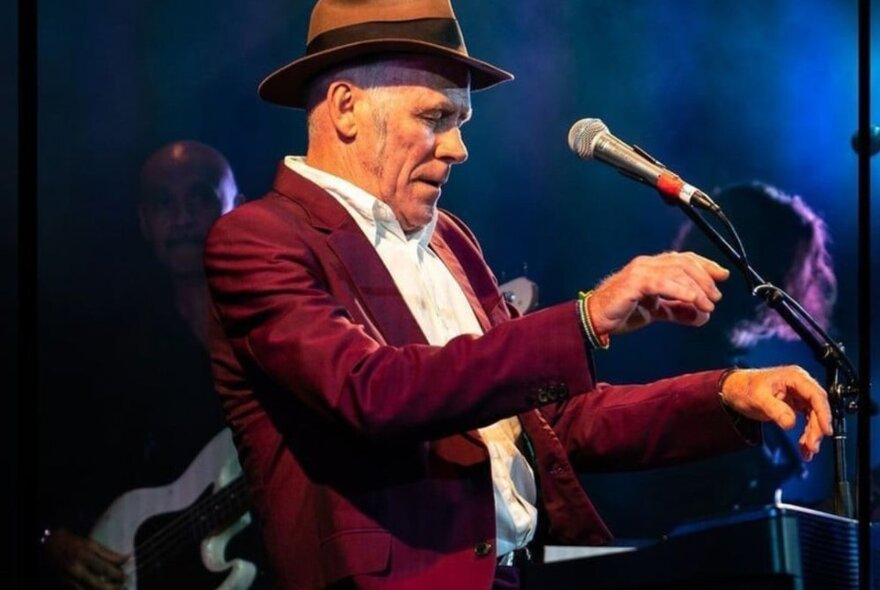 Stewart D'Arrietta performing at a piano with hands poised. 