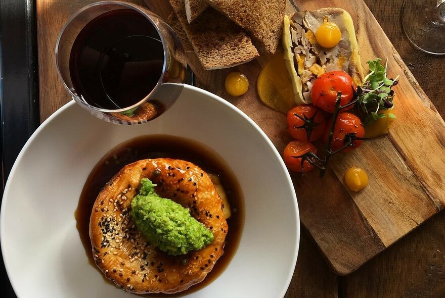 Indoor table with glass of wine, pie with pea mash and board with pate and bread.