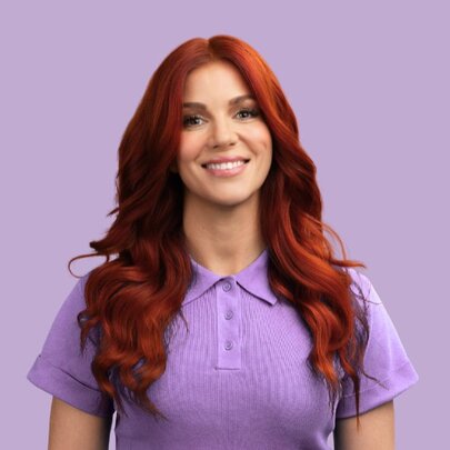 Australian comedian and writer Bron Lewis, wearing a purple top posed against a purple background.