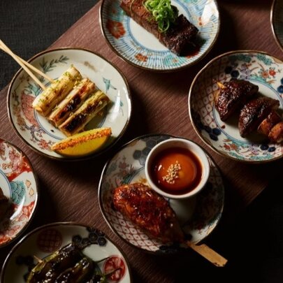 An array of Japanese food presented in small dishes, seen from above on a narrow wooden table.