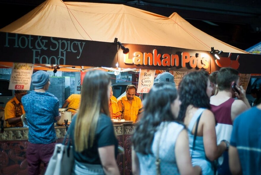 People walking past hot, spicy Sri Lankan food at a cafe in Queen Victoria Market.