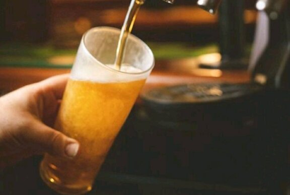 A bartender filling a pint glass with beer from a beer tap.