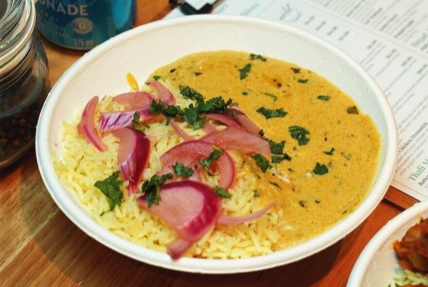 Dahl and rice dish garnished with red onion slices.