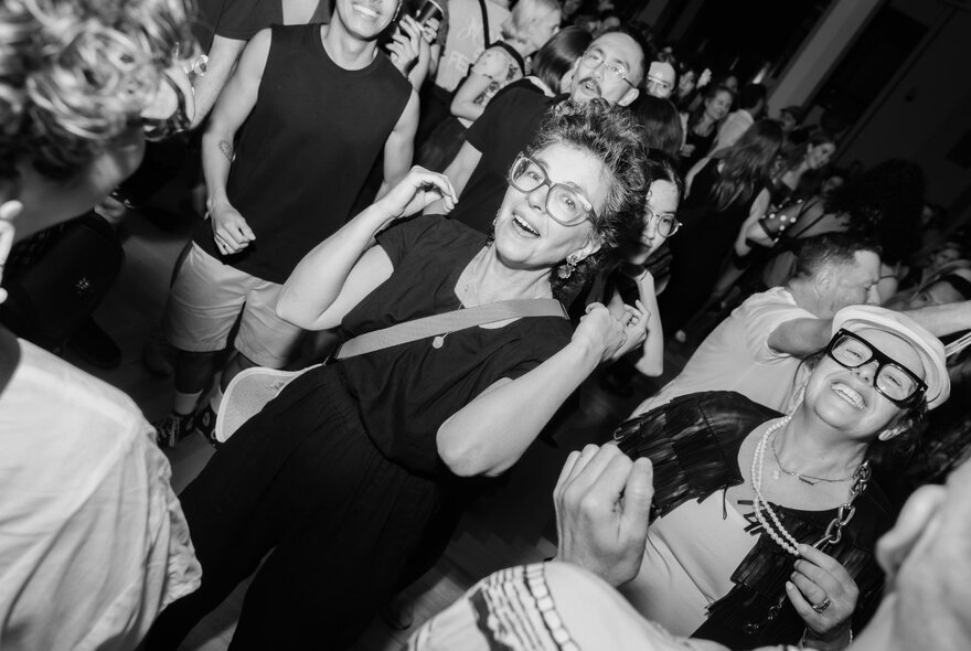 Black and white photograph of revellers in a nightclub enjoying music.