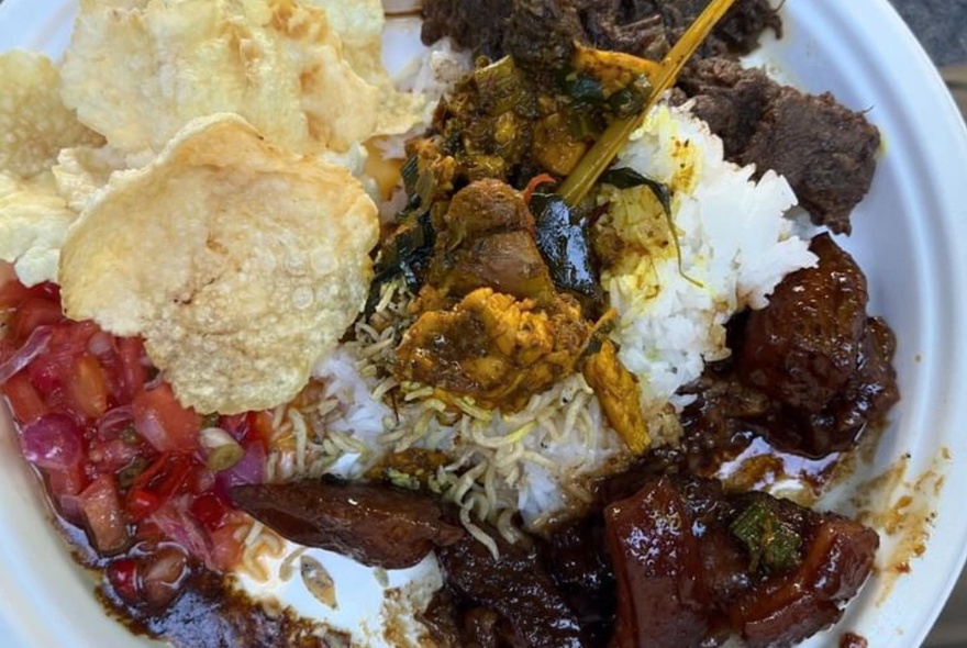 A dish of Indonesian food with rice, puffs and meat.