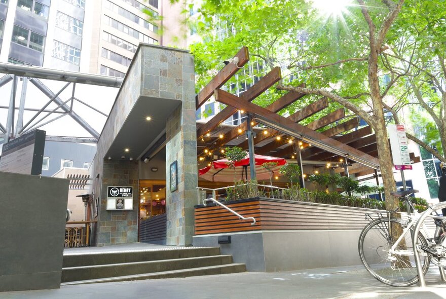 Restaurant exterior with pergola dining area and concrete entry.