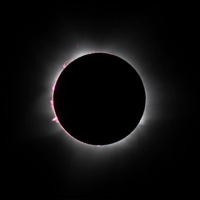 A solar eclipse, with light emerging around the edges of the blacked-out sun.