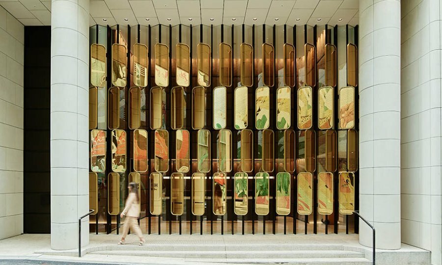 A woman walking past a luxury hotel with a gold mirrored art wall. 