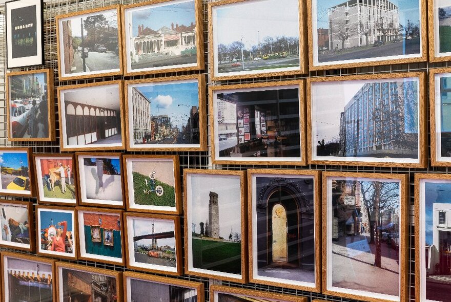 A wall covered in framed images and photographs and displayed very close together.