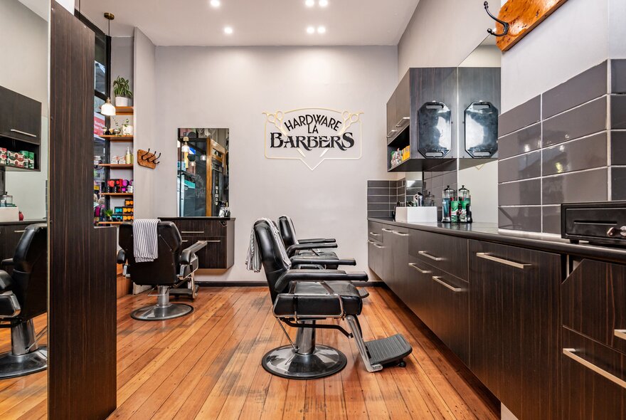 Interior of a barber's shop with empty chairs and signage on the wall. 