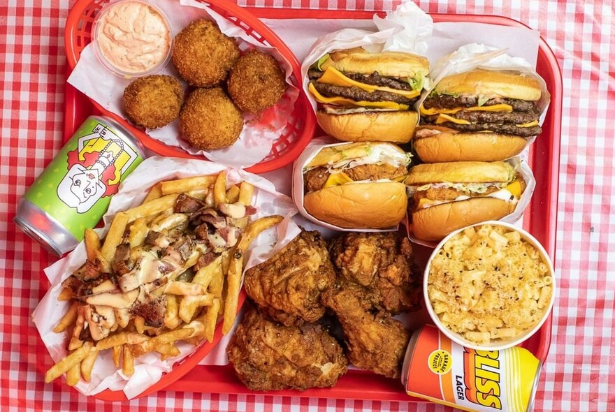 Tray of fast food including hamburgers, chips and fried chicken.