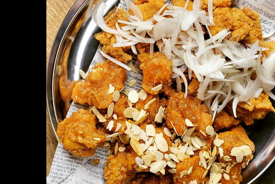 Overhead looking down on plate of crispy fried chicken pieces garnished with sliced onion.