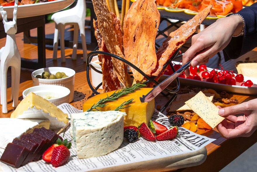 A cheese board with different cheeses, crackers and toasted bread.