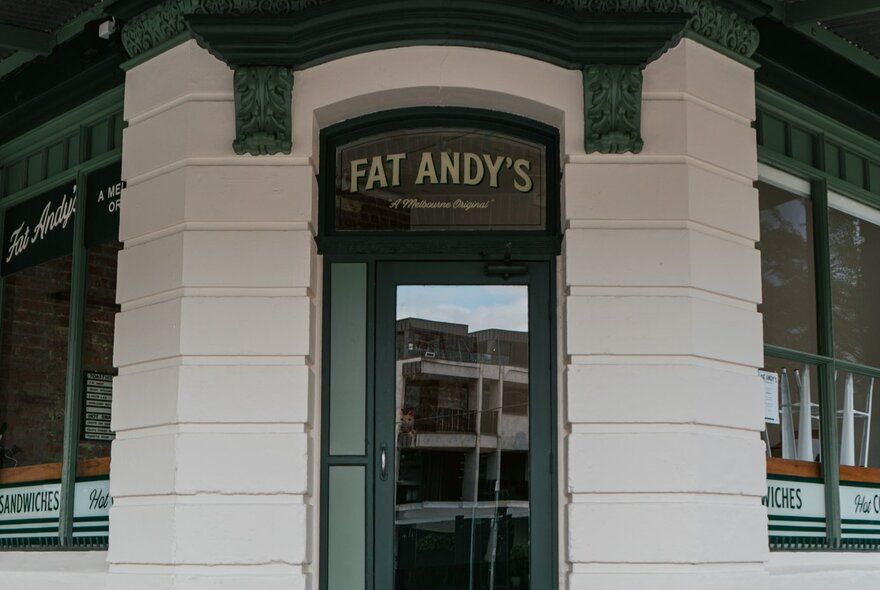 The corner doorway of Melbourne sandwich shop, Fat Andy's, with cream brickwork and dark green accents.