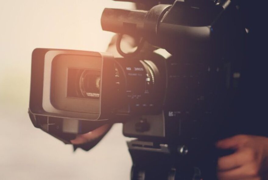 Close up of a film camera, with a person behind controlling it.