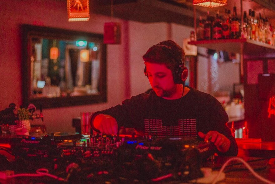 A DJ spinning tracks in a darkened bar.