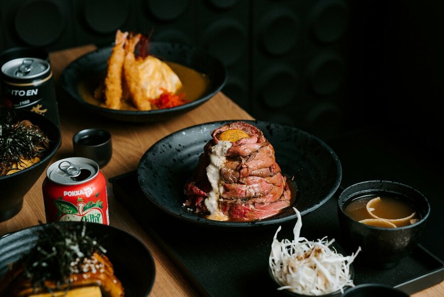 Plates of food and cans of Japanese beer on a table in a restaurant.