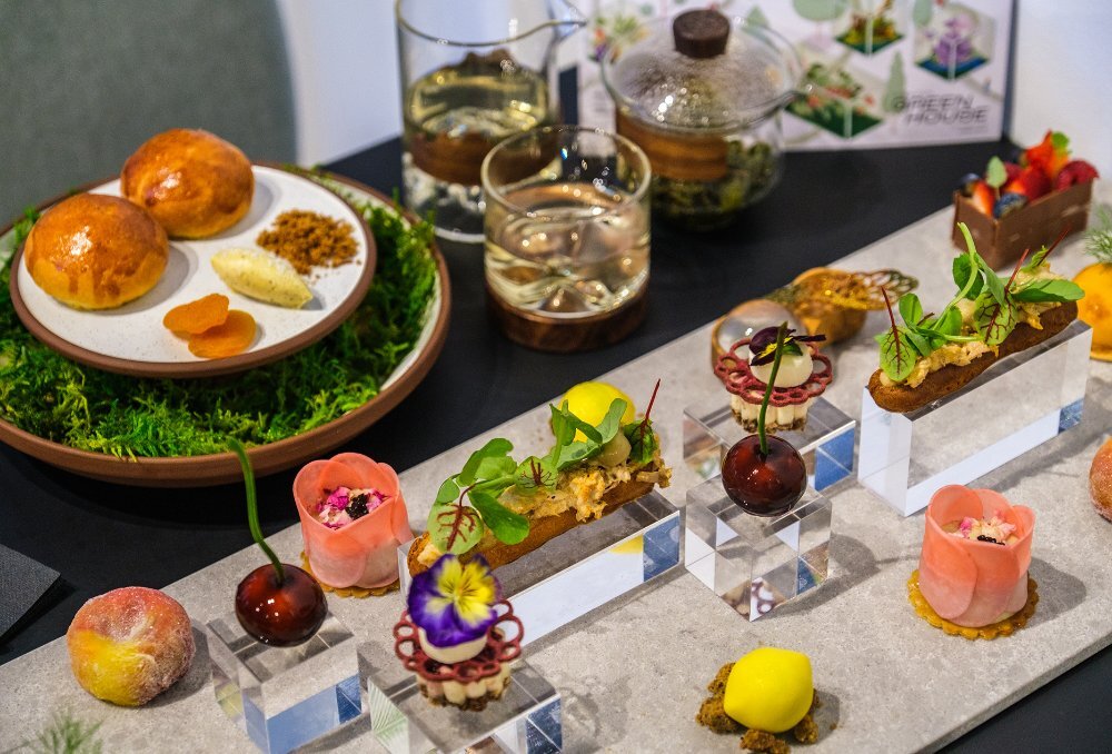 A table set with high tea dishes shaped like fruits and flowers.