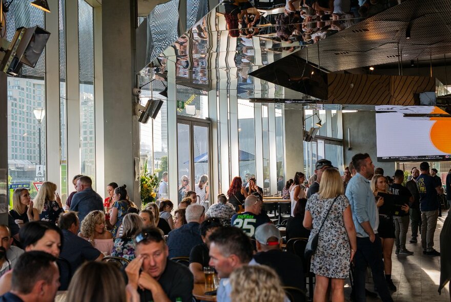 Patrons at a restaurant with wall-to-wall windows during the day.