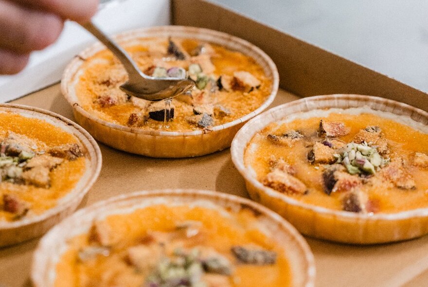 Bowls of orange dessert in a cardboard box.