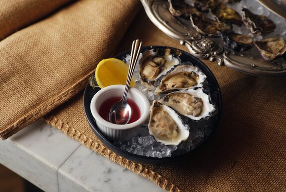 A tray of oysters with a dish of sauce.