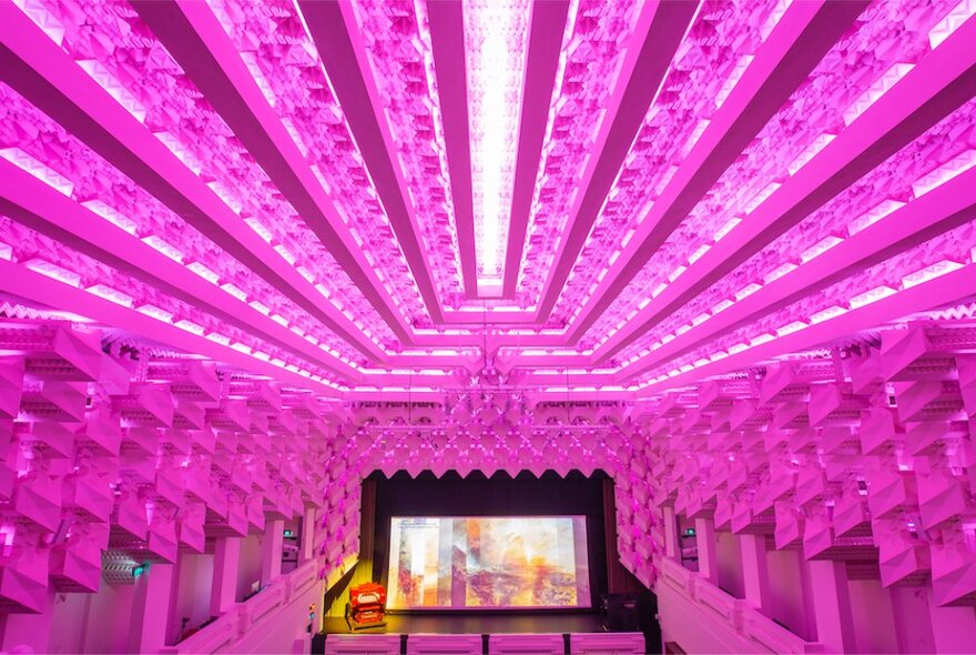 Capitol Cinema interior with brilliant pink lighting and large illumainted screen.