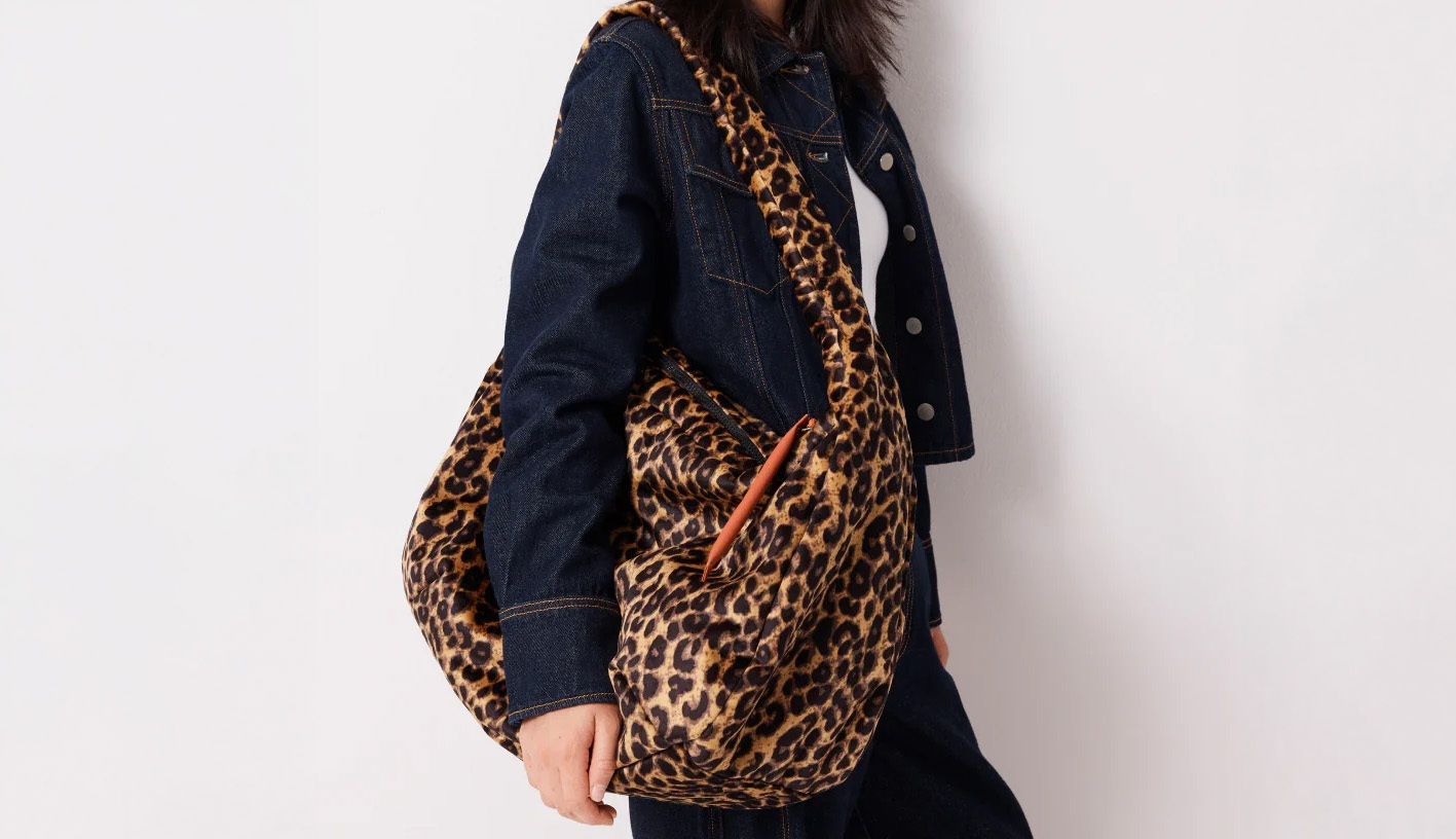 A model wearing a slouchy leopard print bag. 