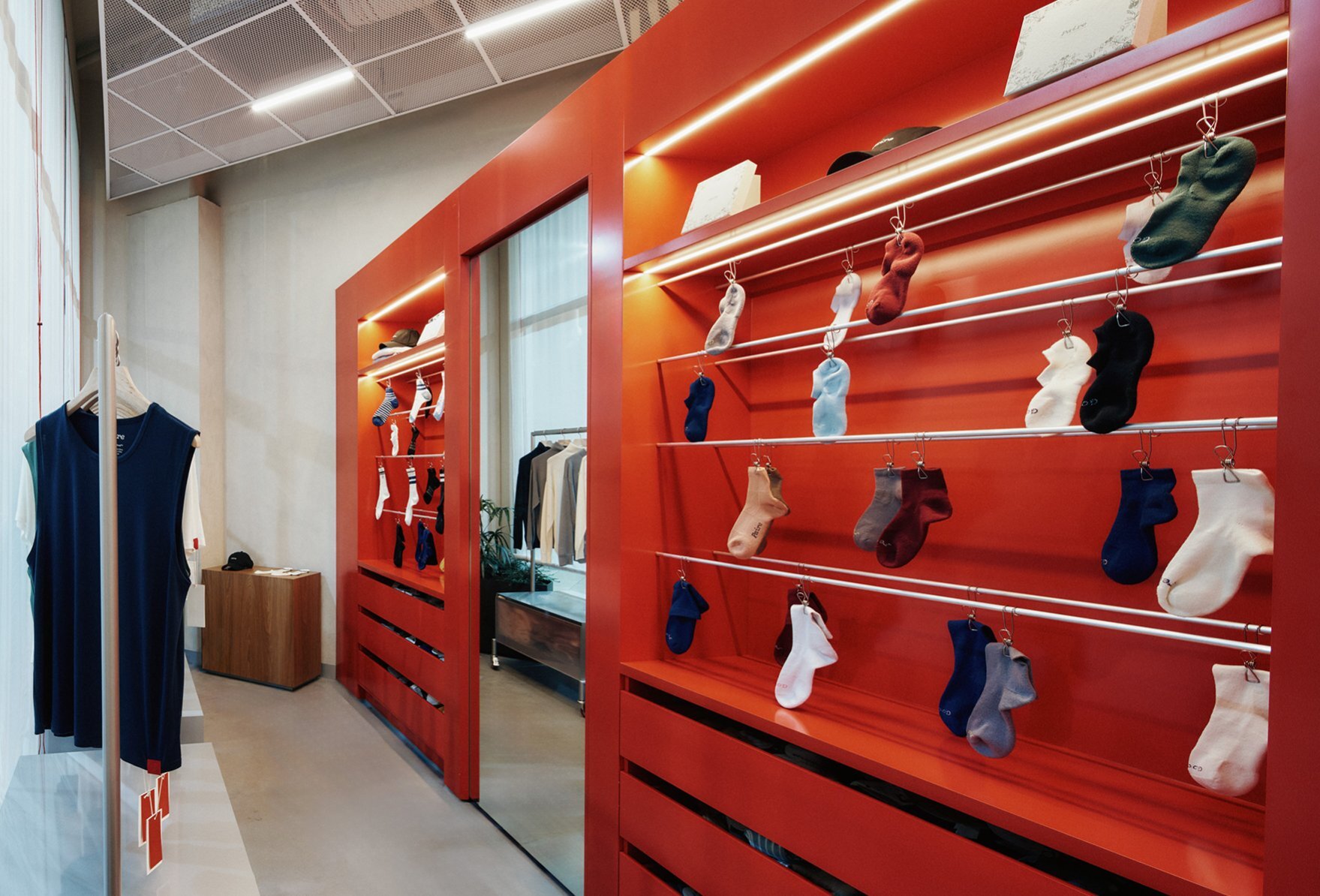 A red wall with socks hanging on display in a shop.
