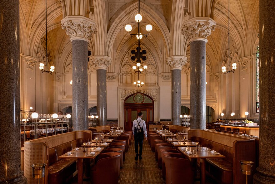 Interior view of the grand and spacious La Reine restaurant showing banquette seating, large marble columns and vaulted ceilings.