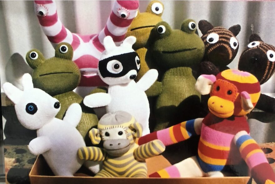 A box of handmade woollen toys in various shades and patterns.