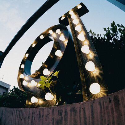 A garden enviroment with a large QT made out of lightbulbs.