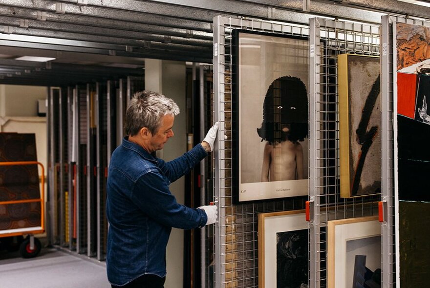 Person handling stored artworks in an archive facility.