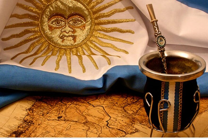Blue and white flag with gold sun emblem, on an old map with silver pot.