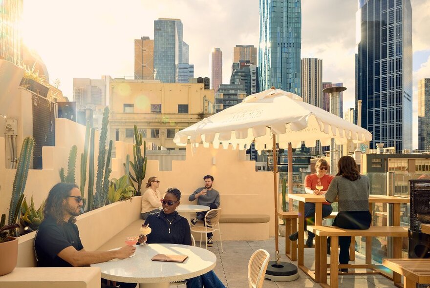 A group of people are drinking cocktails on a rooftop bar