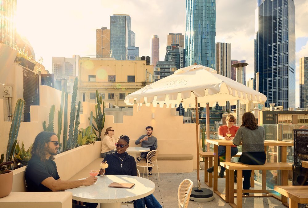 A group of people are drinking cocktails on a rooftop bar