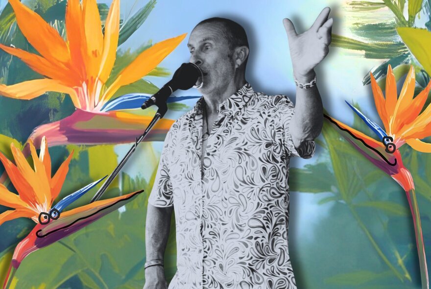 Man at microphone with hand raised surrounded by bird of paradise flowers.