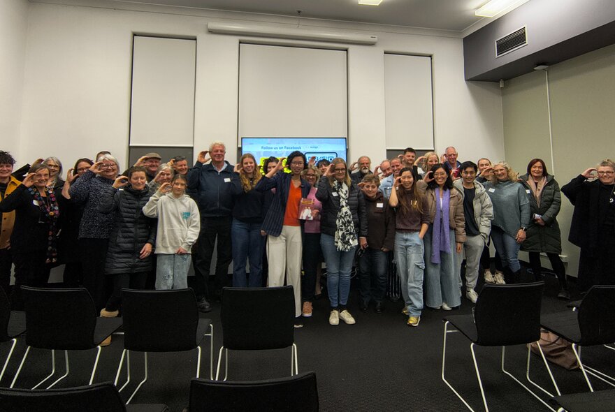 A group of smiling people posing in a room for a photo at a book talk.