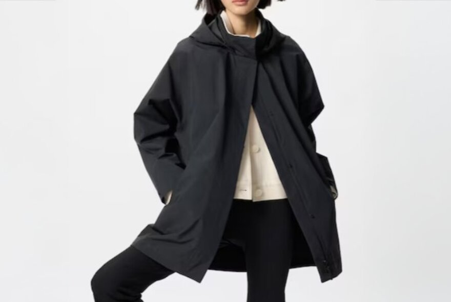 A model wearing a black coat buttoned at the neck.