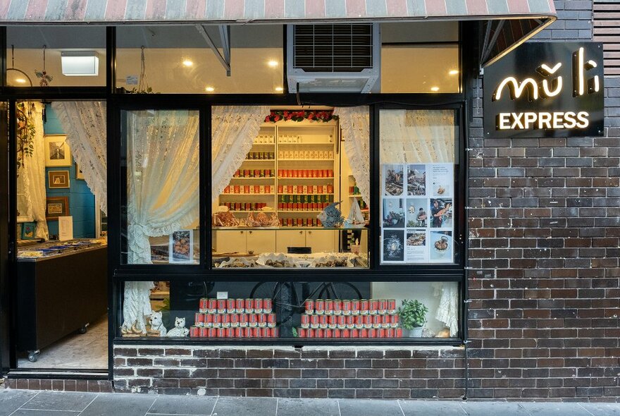 A storefront with lace curtains and a sign reading Muli Express.