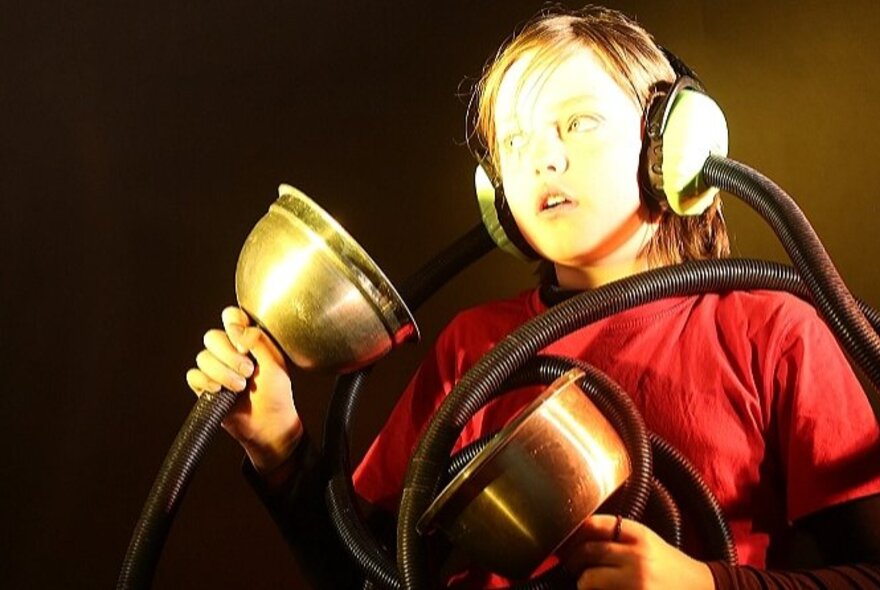 A child listening with a metal ear muff contraption.