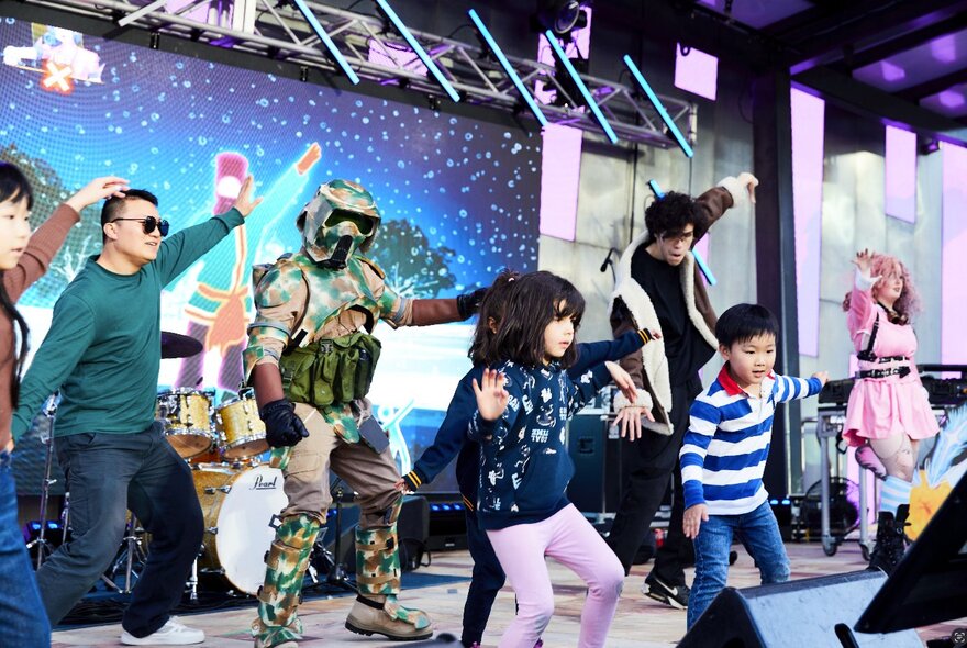 Adults, children and a Star Wars warrior dancing on stage.